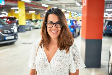 Young woman smiling confident at underground parking lot around cars and lights