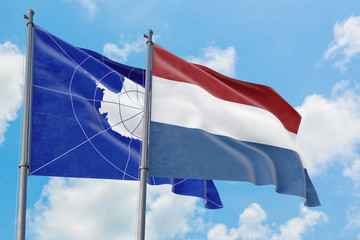 Netherlands and Antarctica flags waving in the wind against white cloudy blue sky together. Diplomacy concept, international relations.