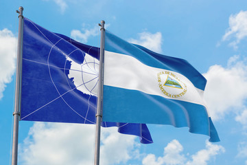 Nicaragua and Antarctica flags waving in the wind against white cloudy blue sky together. Diplomacy concept, international relations.