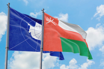 Oman and Antarctica flags waving in the wind against white cloudy blue sky together. Diplomacy concept, international relations.