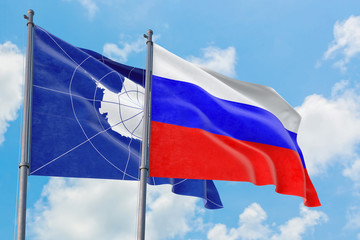 Russia and Antarctica flags waving in the wind against white cloudy blue sky together. Diplomacy concept, international relations.