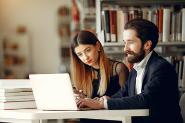 Students in a library. Guy in a black suit. Student with a books.