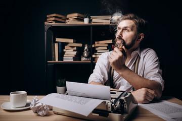 Handsome bearded writer thinking, smoking pipe and looking upwards