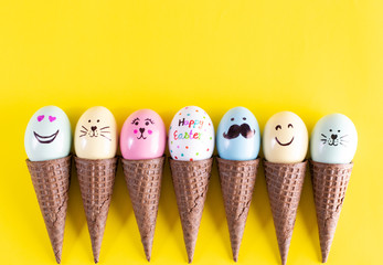 Row of hand painted Easter eggs in waffle cones on a yellow background. Easter egg concept.
