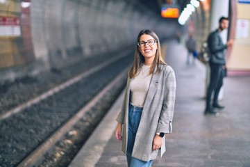 Fototapeta premium Young beautiful woman smiling happy and confident. Standing with smile on face at platform of train station