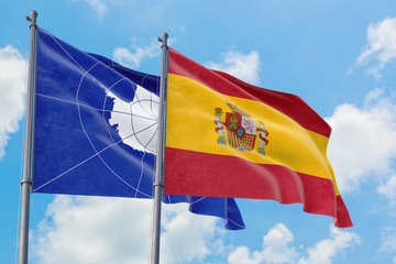 Spain and Antarctica flags waving in the wind against white cloudy blue sky together. Diplomacy concept, international relations.