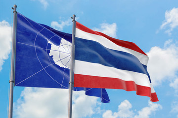 Thailand and Antarctica flags waving in the wind against white cloudy blue sky together. Diplomacy concept, international relations.