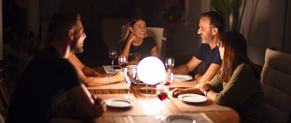 Beautiful family on dinner talking and smiling at terrace