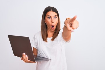 Beautiful young woman working using computer laptop over white background Pointing with finger surprised ahead, open mouth amazed expression, something on the front
