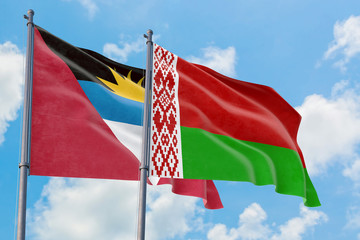 Belarus and Antigua and Barbuda flags waving in the wind against white cloudy blue sky together. Diplomacy concept, international relations.