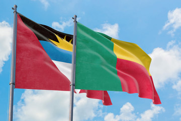 Benin and Antigua and Barbuda flags waving in the wind against white cloudy blue sky together. Diplomacy concept, international relations.