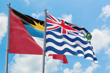 British Indian Ocean Territory and Antigua and Barbuda flags waving in the wind against white cloudy blue sky together. Diplomacy concept, international relations.