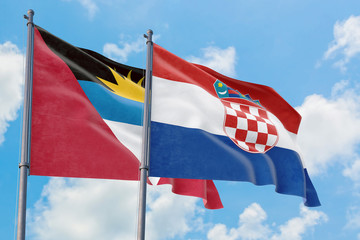 Croatia and Antigua and Barbuda flags waving in the wind against white cloudy blue sky together....