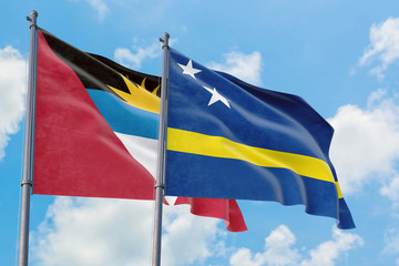 Curacao and Antigua and Barbuda flags waving in the wind against white cloudy blue sky together. Diplomacy concept, international relations.