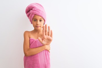 Beautiful child girl wearing shower towel after bath standing over isolated white background doing stop sing with palm of the hand. Warning expression with negative and serious gesture on the face.