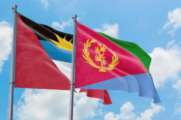 Eritrea and Antigua and Barbuda flags waving in the wind against white cloudy blue sky together. Diplomacy concept, international relations.