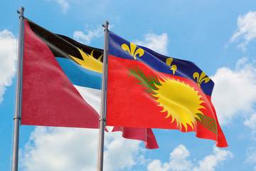 Guadeloupe and Antigua and Barbuda flags waving in the wind against white cloudy blue sky together. Diplomacy concept, international relations.
