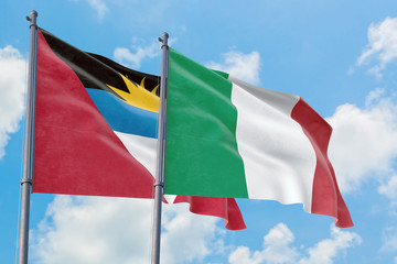 Italy and Antigua and Barbuda flags waving in the wind against white cloudy blue sky together. Diplomacy concept, international relations.