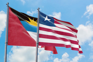 Liberia and Antigua and Barbuda flags waving in the wind against white cloudy blue sky together. Diplomacy concept, international relations.