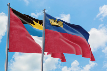 Liechtenstein and Antigua and Barbuda flags waving in the wind against white cloudy blue sky together. Diplomacy concept, international relations.