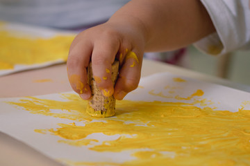Child's hand sealing with cork and yellow painting