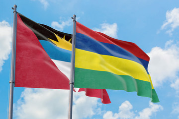 Mauritius and Antigua and Barbuda flags waving in the wind against white cloudy blue sky together. Diplomacy concept, international relations.