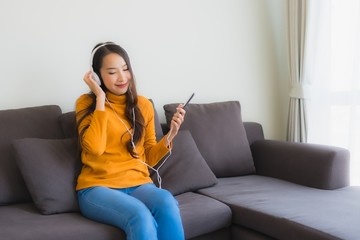 Obraz premium Portrait young asian woman using smart mobile phone with headphone for listen music on sofa