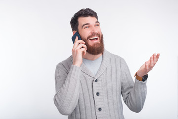 Young man is having a wonderful converation on his phone. He is talking and gesturing on white background.