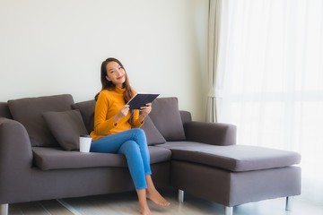 Portrait young asian woman read book on sofa chair with pillow in living room