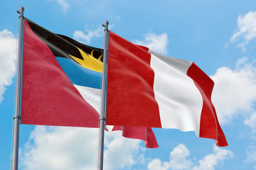 Peru and Antigua and Barbuda flags waving in the wind against white cloudy blue sky together. Diplomacy concept, international relations.