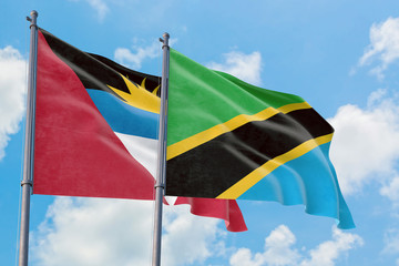 Tanzania and Antigua and Barbuda flags waving in the wind against white cloudy blue sky together. Diplomacy concept, international relations.