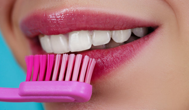 Teeth with tooth brush. Clean teeth. Perfect womans smile. Healthy white theeth. Beauty woman with perfect lips and smile. Dental care and teeth whitening. Close-up of perfect smile with tooth brush.