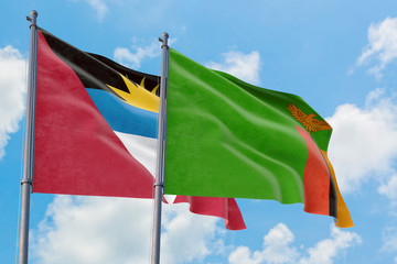 Zambia and Antigua and Barbuda flags waving in the wind against white cloudy blue sky together. Diplomacy concept, international relations.