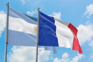 France and Argentina flags waving in the wind against white cloudy blue sky together. Diplomacy concept, international relations.