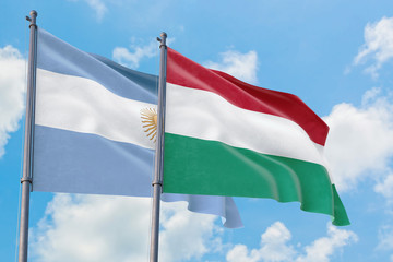 Hungary and Argentina flags waving in the wind against white cloudy blue sky together. Diplomacy concept, international relations.