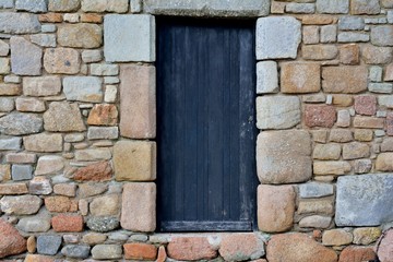 Fototapeta premium Beautiful door on a pink granite stones wall in Brittany France