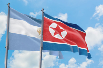 North Korea and Argentina flags waving in the wind against white cloudy blue sky together. Diplomacy concept, international relations.
