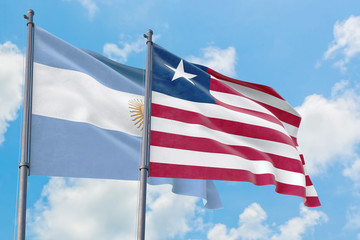Liberia and Argentina flags waving in the wind against white cloudy blue sky together. Diplomacy concept, international relations.