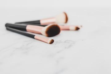 group of make-up brushes for face and eyes on marble tabletop at shallow depth of field