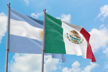 Mexico and Argentina flags waving in the wind against white cloudy blue sky together. Diplomacy concept, international relations.