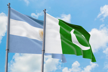 Pakistan and Argentina flags waving in the wind against white cloudy blue sky together. Diplomacy concept, international relations.