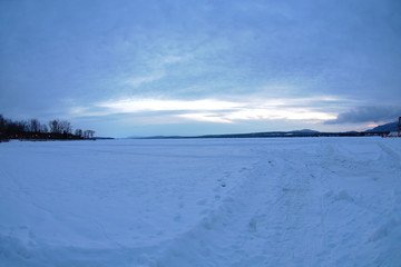 Fototapeta na wymiar frozen lake winter landscape ice and snow dusk