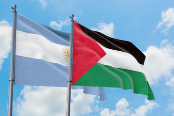 Palestine and Argentina flags waving in the wind against white cloudy blue sky together. Diplomacy concept, international relations.