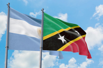 Saint Kitts And Nevis and Argentina flags waving in the wind against white cloudy blue sky together. Diplomacy concept, international relations.