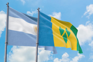 Saint Vincent And The Grenadines and Argentina flags waving in the wind against white cloudy blue sky together. Diplomacy concept, international relations.