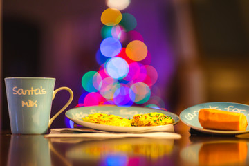 santas milk, cookies, and carrot for reindee with bokeh christmas tree