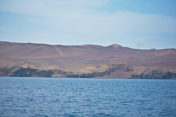 Ocean landscape sunny with a sandy mountain in the background in Paracas Peru