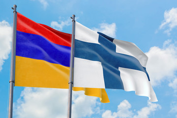 Finland and Armenia flags waving in the wind against white cloudy blue sky together. Diplomacy concept, international relations.