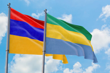 Gabon and Armenia flags waving in the wind against white cloudy blue sky together. Diplomacy concept, international relations.