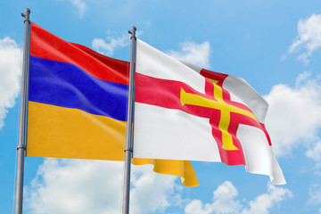 Guernsey and Armenia flags waving in the wind against white cloudy blue sky together. Diplomacy concept, international relations.